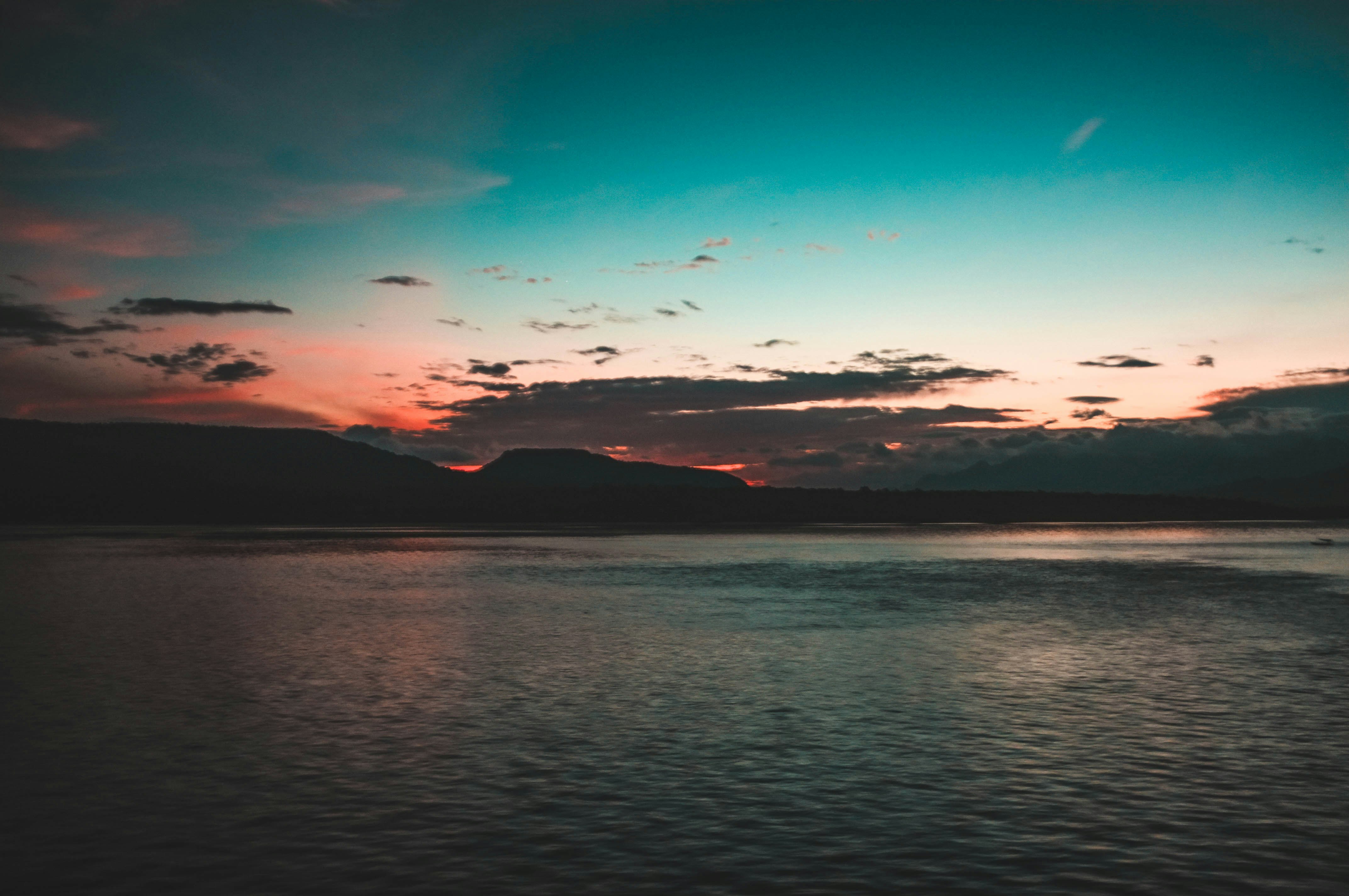 sea near mountain silhouette during blue hour